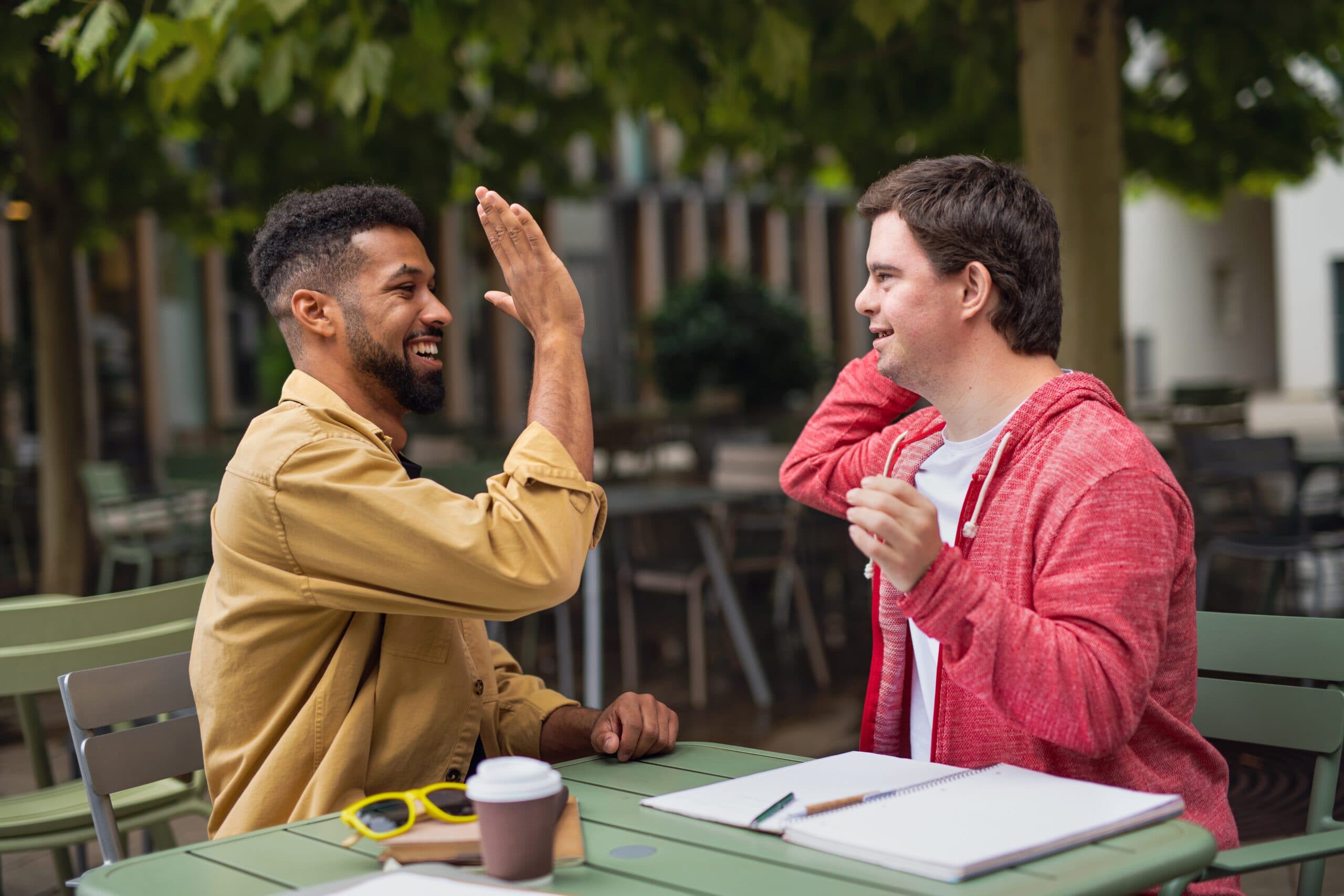 Activiteitenbegeleider en cliënt geven elkaar een high five tijdens dagbesteding